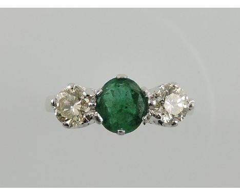 A diamond and emerald dress ring, claw set in a white metal band stamped 18kt, 3.5g.