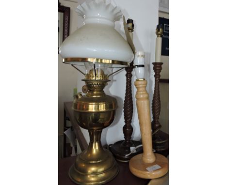 A brass oil lamp with white opaque glass shade, together with three turned wooden table lamps and a standard lamp