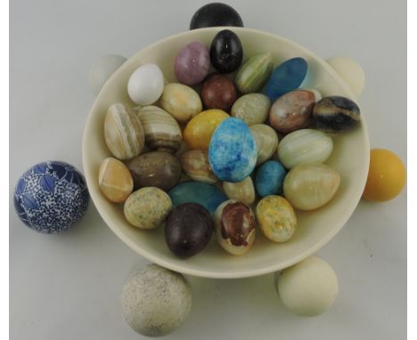 A collection of hardstone eggs, within a white ceramic bowl.