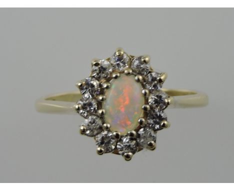 A opal dress ring, set within a hoop of white stones on a yellow metal band stamped 9ct, 1.9g.