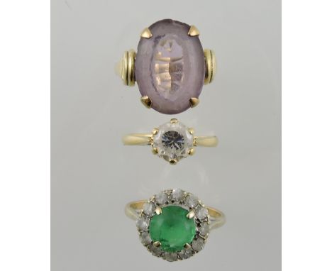 A green stone dress ring, the central claw setting within a hoop of white stones on a yellow metal band stamped 9ct; together