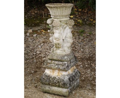 A RECONSTITUTED STONE SMALL PLANTER of ribbed form supported by putti and on a square plinth base, 76cm high overall