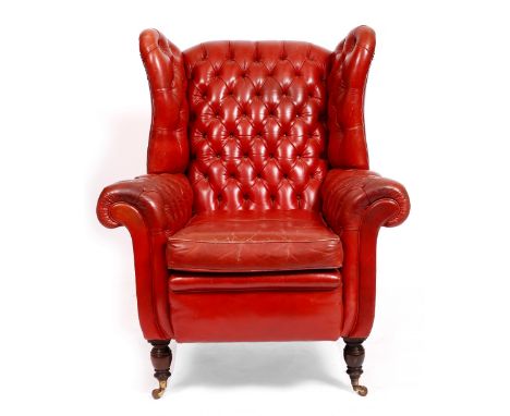 A LATE 19TH CENTURY RED LEATHER BUTTON UPHOLSTERED WING BACK ARMCHAIR of large proportions, having turned feet and ceramic ca