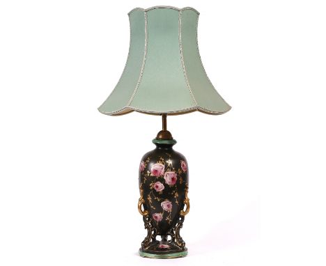 AN OLD POTTERY TABLE LAMP  decorated with roses on a black ground and with circular base, 80cm high including the shade