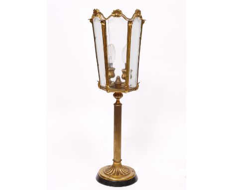 A GILT METAL TABLE LAMP  with six glass lantern type shade around the two lights within, all on a reeded stem and spreading c