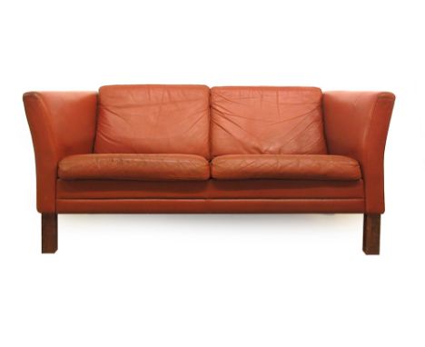 A 1970's red leather two seater sofa on stained beech legs CONDITION REPORT: Wear. Structurally sound.