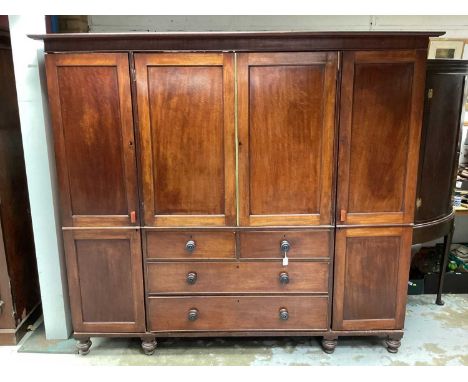 19th century mahogany compactum wardrobe with central chest of four drawers, press above, flanked by hanging spaces on turned