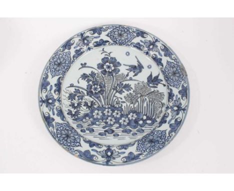 A blue and white Dutch delftware dish, circa 1700, painted in the Oriental style with birds amongst flowers, with a foliate-p