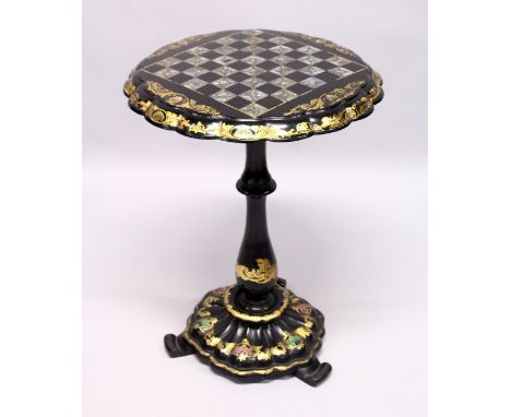 A VICTORIAN BLACK AND GILT PAPIER MACHE TILT TOP GAMES TABLE, with inlaid chess board in mother of pearl. 1ft 8ins wide, 2ft 