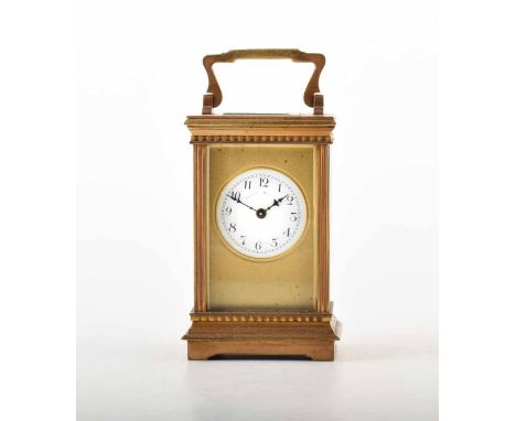 A brass French carriage clock. With brass carry handle and fluted detail on the case, round enamel face, Arabic numerals and 
