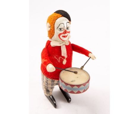 A Schuco tinplate clockwork Drumming Clown, black felt beret over ginger hair and painted tinplate face, wearing a red jacket