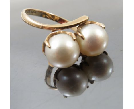 A two stone pearl crossover ring, stamped 'K14', the pearls (untested and unwarranted) of approximately 7.5mm diameter, finge