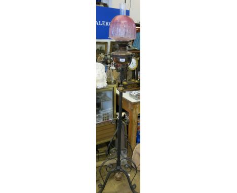 A wrought iron oil lamp stand, with twisted and scroll decoration, having an adjustable height for the oil lamp base, with gl