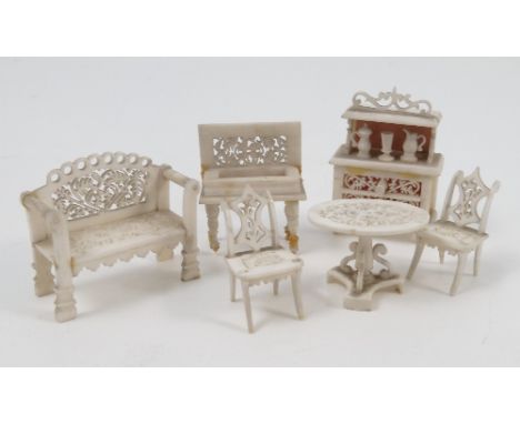 A group of 19th century carved ivory miniature furniture, to include a settee, an oval table, two chairs, a dresser and a sew