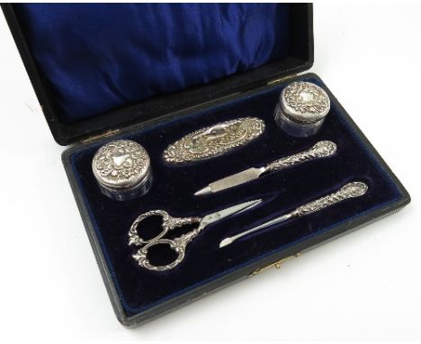 A cased six piece ladies manicure set, comprising two silver topped jars, a silver mounted nail buffer, pair of silver handle