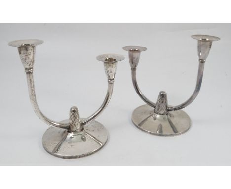 A pair of A E Jones silver two light candelabrum, the curved branches supporting the candle holders at differing levels, rais