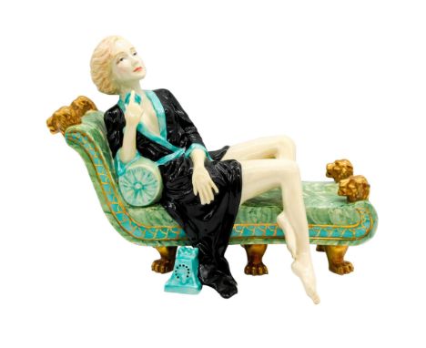 Art Deco figure of actress in black and turquoise, lounging on a jade-color chaise holding a phone in her right hand. Special