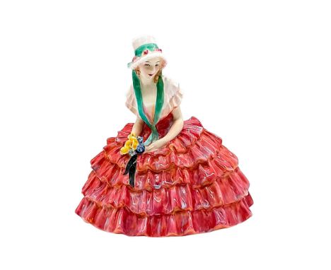 Rare red version. A figure of a seated woman in a red skirt and a pink bonnet with a green sash. Royal Doulton backstamp. Mod