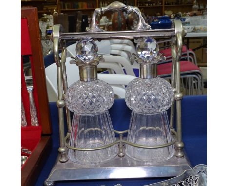 A silver plated double tantalus, with a pair of thistle-shape cut-glass decanters and stoppers with plated mounts, unsigned 