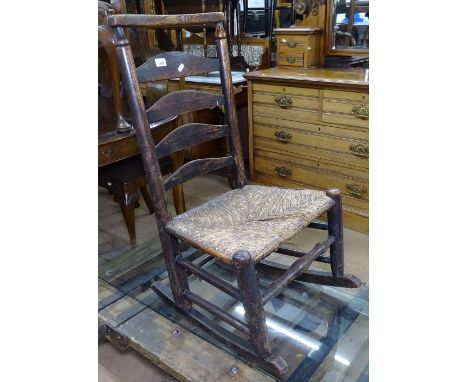 An Antique oak ladder-back rocking chair with rush-seat 