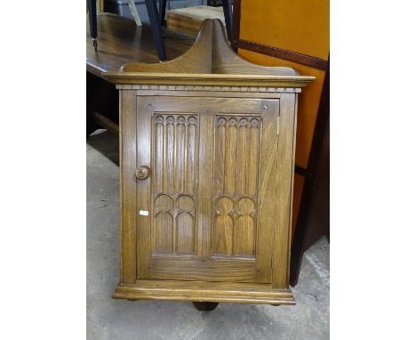 An Ercol elm hanging corner cupboard with panel door 