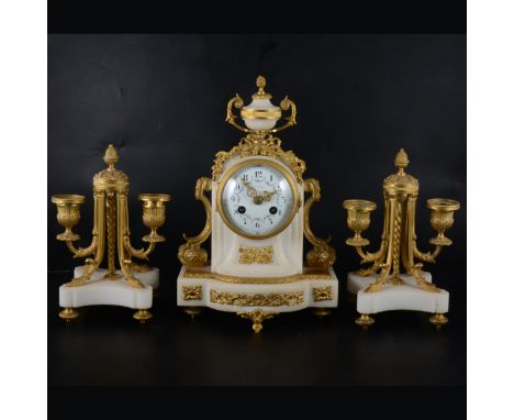 A Louis XV style white marble and gilt metal three-piece clock garniture, clock with an urn surmount, and scroll volutes, whi