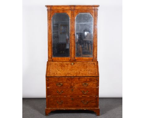 A George II walnut bureau bookcase, breakfront cavetto cornice, tapering pilasters, the upper section with two arched bevelle