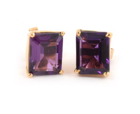 A pair of amethyst stud earrings, the rectangular step cut stones, 10mm x 8mm. four claw set in yellow metal settings with po