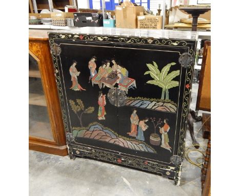 Oriental lacquered cabinet, overall decoration of figures around a gaming board with plants, pair of panelled doors enclosing