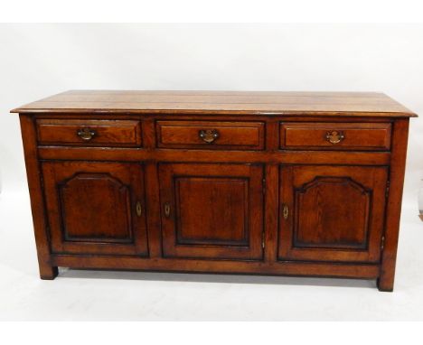 Georgian style oak dresser base, with three frieze drawers and shaped fielded cupboards below enclosing shelf on stile suppor