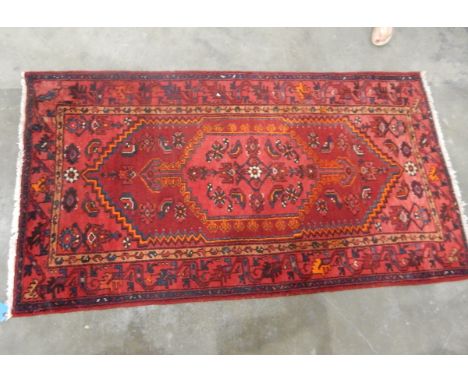 Persian wool rug with ruby red field, central herati and trailing stylised leaf borders, 203cm x 112cm 