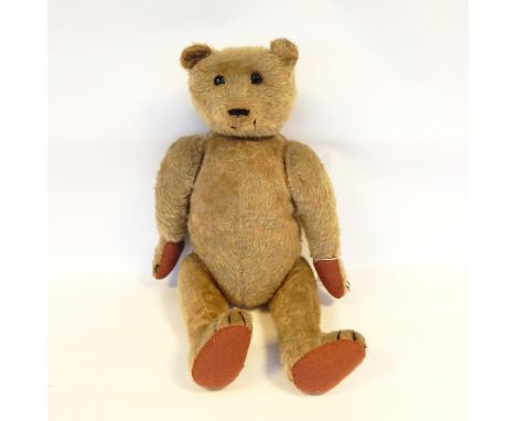 Old plush bodied teddy bear, straw filled, articulated limbs, hump back, glass bead eyes, sewn nose, 40cm long (with later fe