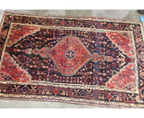 Eastern wool rug with midnight blue field and geometric ruby red arabesque to centre, ruby red spandrels, stylised flowerhead