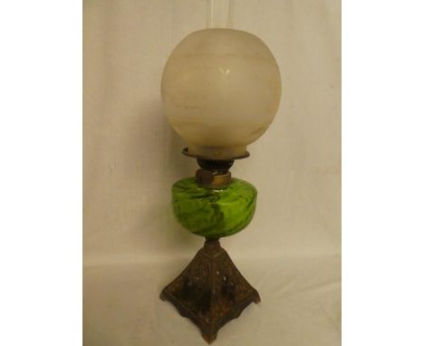 A Victorian cast iron and brass oil lamp with green tinted glass reservoir and etched glass shade
