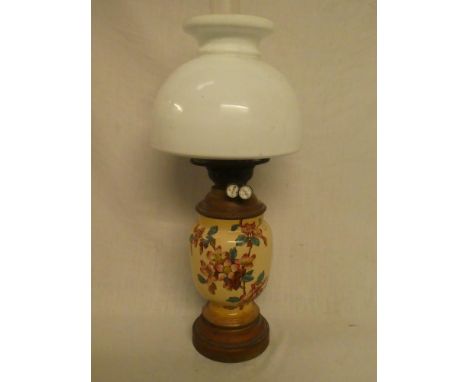 A Victorian brass and ceramic baluster-shaped oil lamp with floral decoration and opaque glass shade