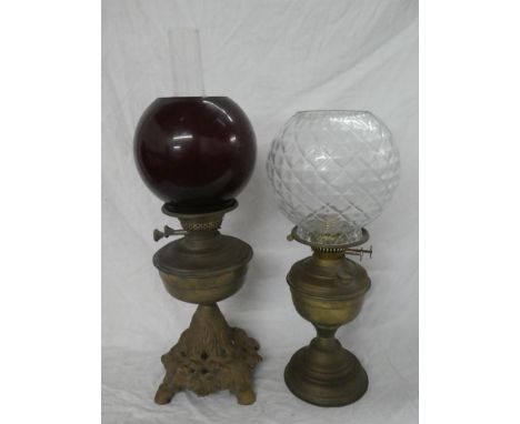 A Victorian cast iron and brass mounted oil lamp with brass reservoir and ruby-tinted glass shade and one other brass oil lam