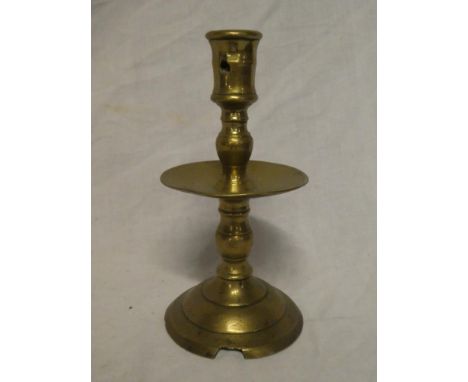 A 17th Century brass candlestick with dished centre on circular base 7 ½" high (slight damage)