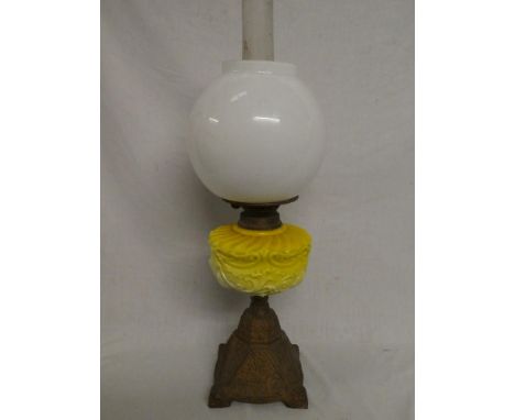 A Victorian cast iron and brass oil lamp with yellow opaque glass reservoir and modern opaque glass shade