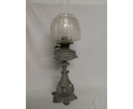 A late Victorian/Edwardian grey metal oil lamp with scroll decoration, brass mounts and etched glass shade (shade damaged)