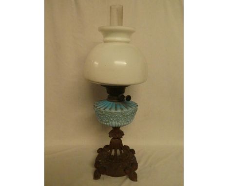 A late Victorian oil lamp with ornate cast iron base, blue opaque glass reservoir and opaque glass shade (tiny edge chips to 