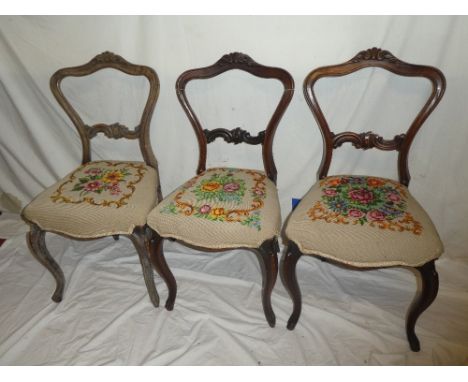 Three matching Victorian carved rosewood dining chairs with rail backs and tapestry seats on scroll legs