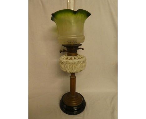 A Victorian brass oil lamp with column stem, ornate opaque glass reservoir and green tinted glass shade (shade with tiny hair