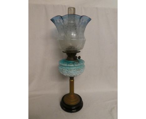 A Victorian brass oil lamp with blue opaque glass floral reservoir and blue-tinted etched glass shade on ceramic base (shade 
