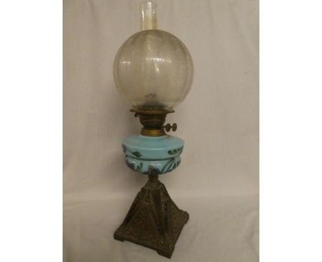 A Victorian cast iron and brass oil lamp with blue opaque glass floral reservoir and etched glass shade