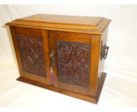 An Edwardian carved oak smoker's cabinet with internal drawers, mixing bowl and pipe racks