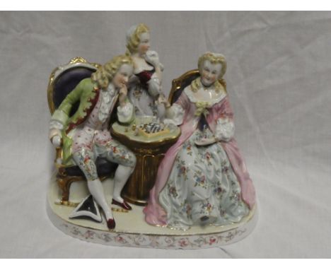 A Continental china figure of a male and female playing chess with other female in attendance, 10" long