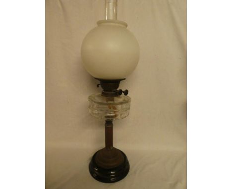 A Victorian brass column oil lamp with clear glass reservoir and pink-tinted glass shade on ceramic base