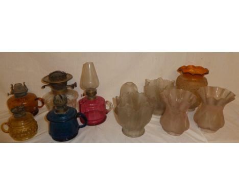 Four various coloured glass chamber oil lamps, a cut glass oil lamp reservoir ans a selection of various small glass shades