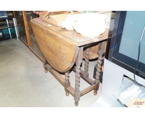 An oak gate leg table raised on barley twist supports