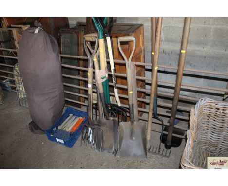 A quantity of long handled tools including forks, spades, shovels, pitch fork, rake etc.